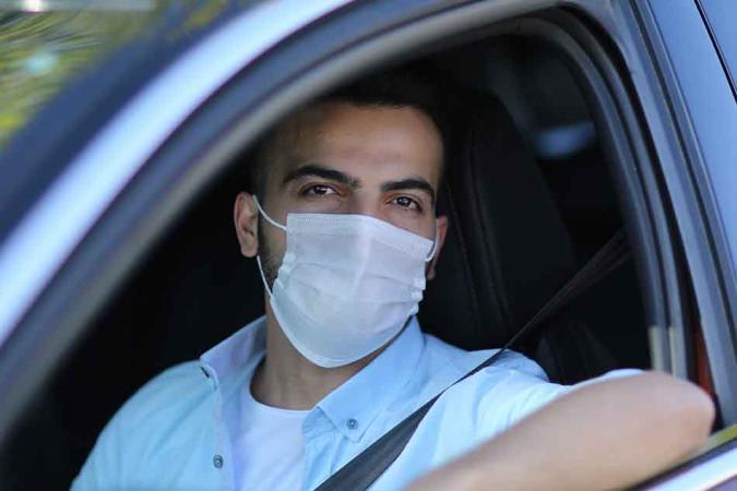 Driver in mask leaning out his car window