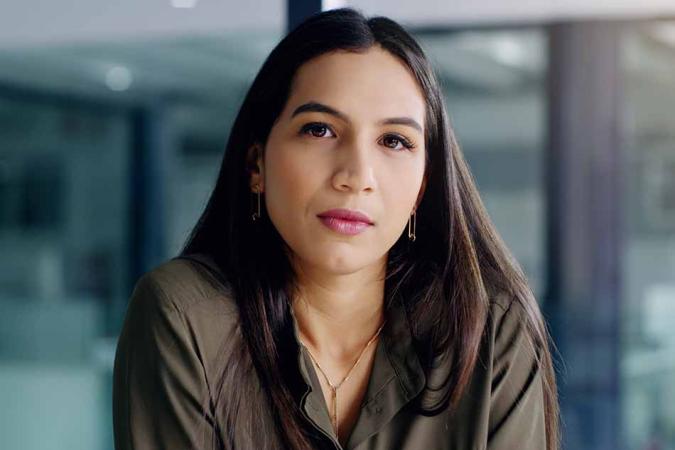 Women in an olive blouse with an office behind her